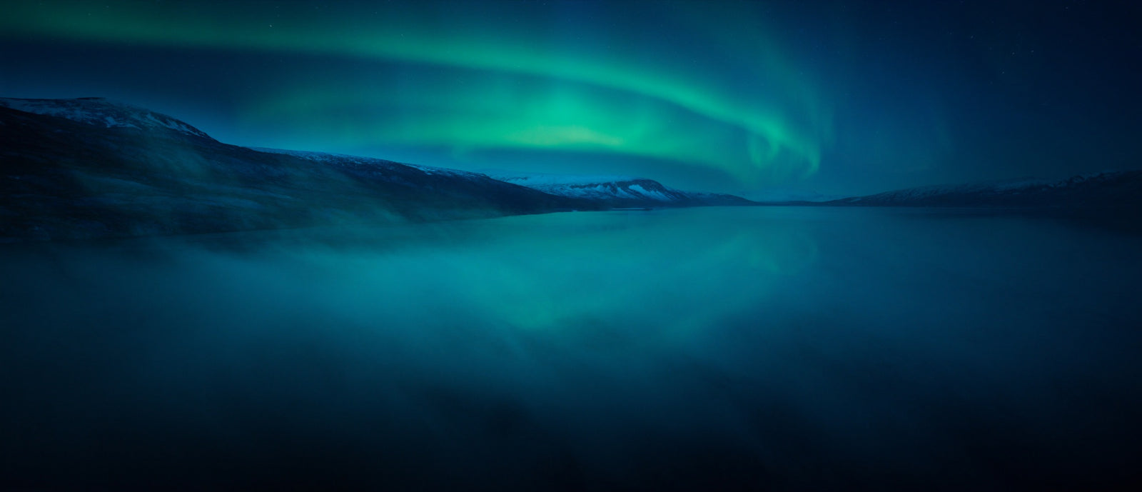 Nordlicht über einem ruhigen Fjord